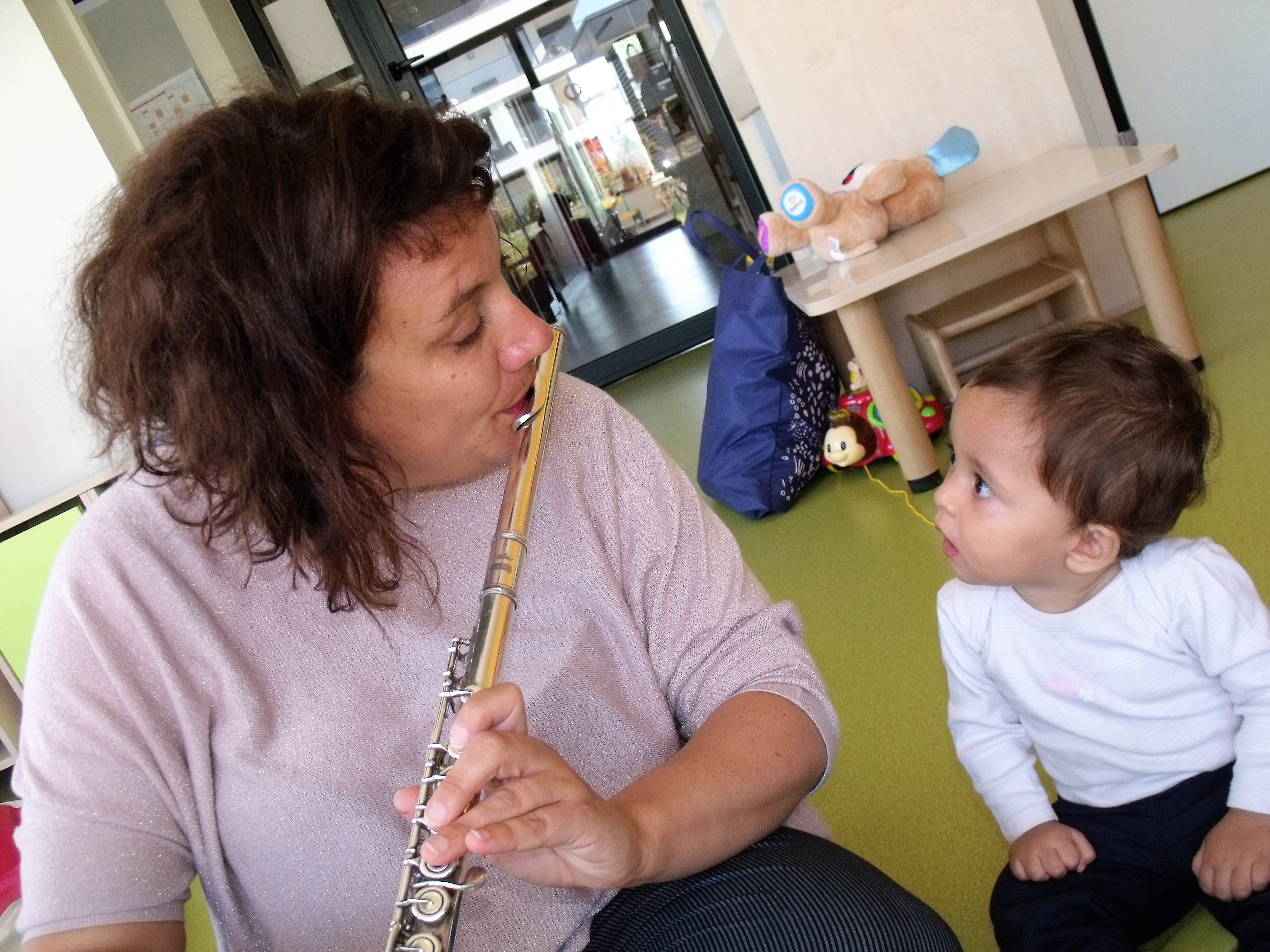Laure la musicienne joue de la flute traversière sous le regard très intéressé et intrigué d&#039;un bébé