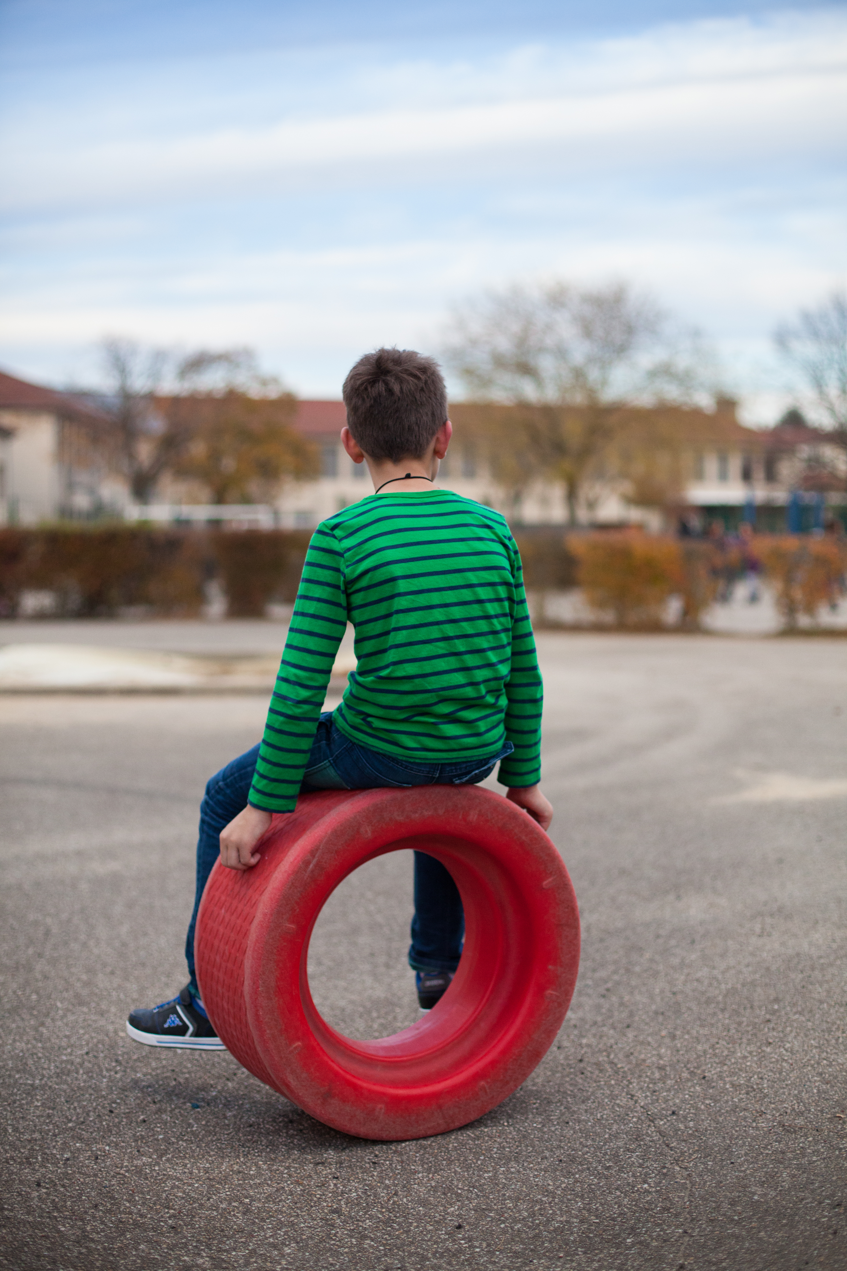 Un enfant assis sur une roue dans la cour