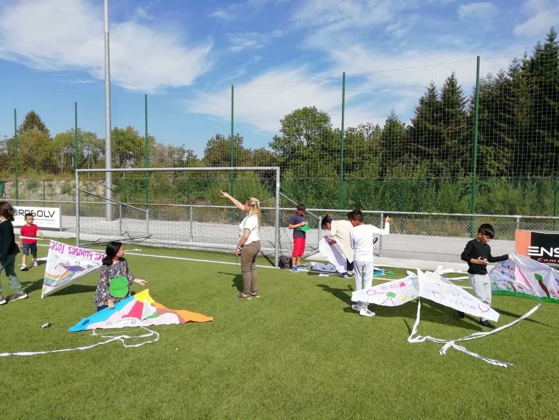 Des enfants sur un terrain de foot en extérieur qui tentent de faire voler leurs cerfs-volants