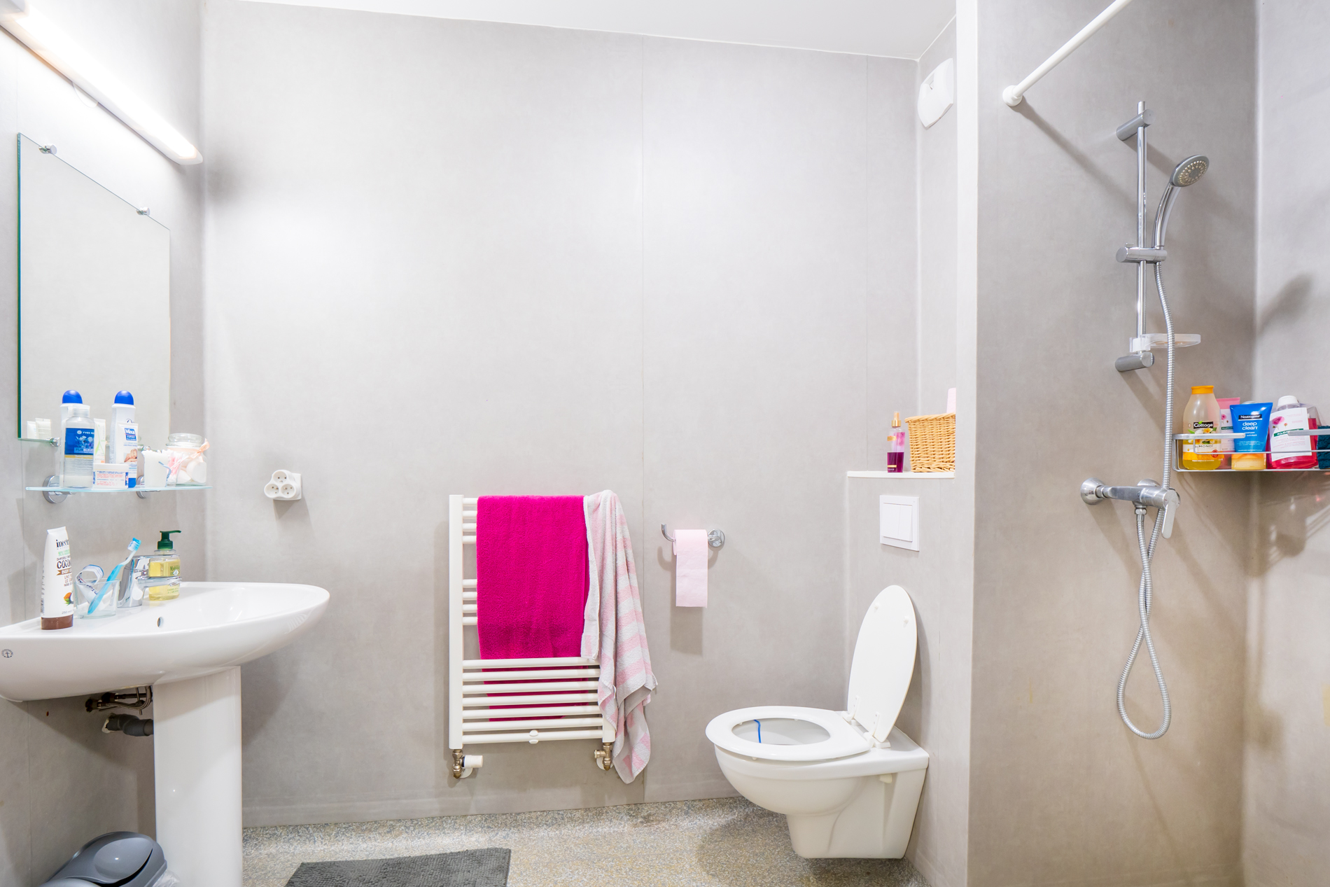 Une salle de bain neuve et spacieuse, comprenant lavabo, toilette, porte-serviette chauffant, et douche.