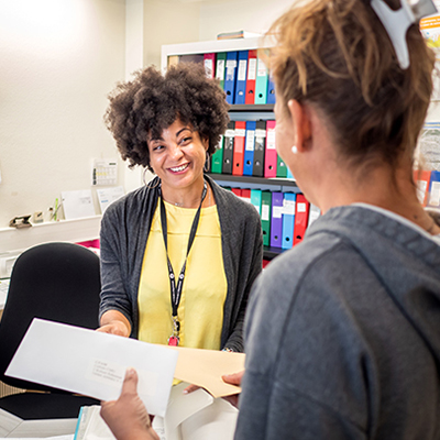 Une salariée souriante accueille une personne suivie dans le cadre du service accompagnement des gens du voyage