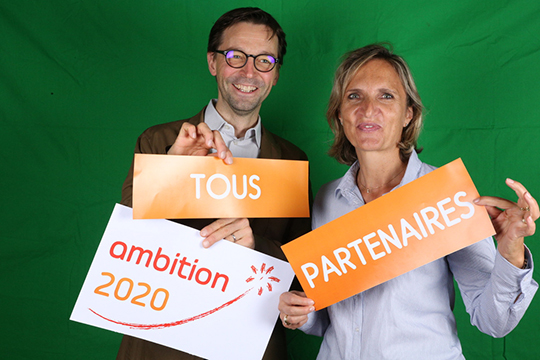 la vice-présidente d&#039;Alfa3a et un prestataire tiennent des pancartes disant &quot;ambition 2020 : tous partenaires&quot;