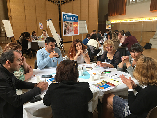 dans une salle polyvalente, des tables d&#039;une dizaine de personnes sont installées et les participants échangent et s&#039;écoutent