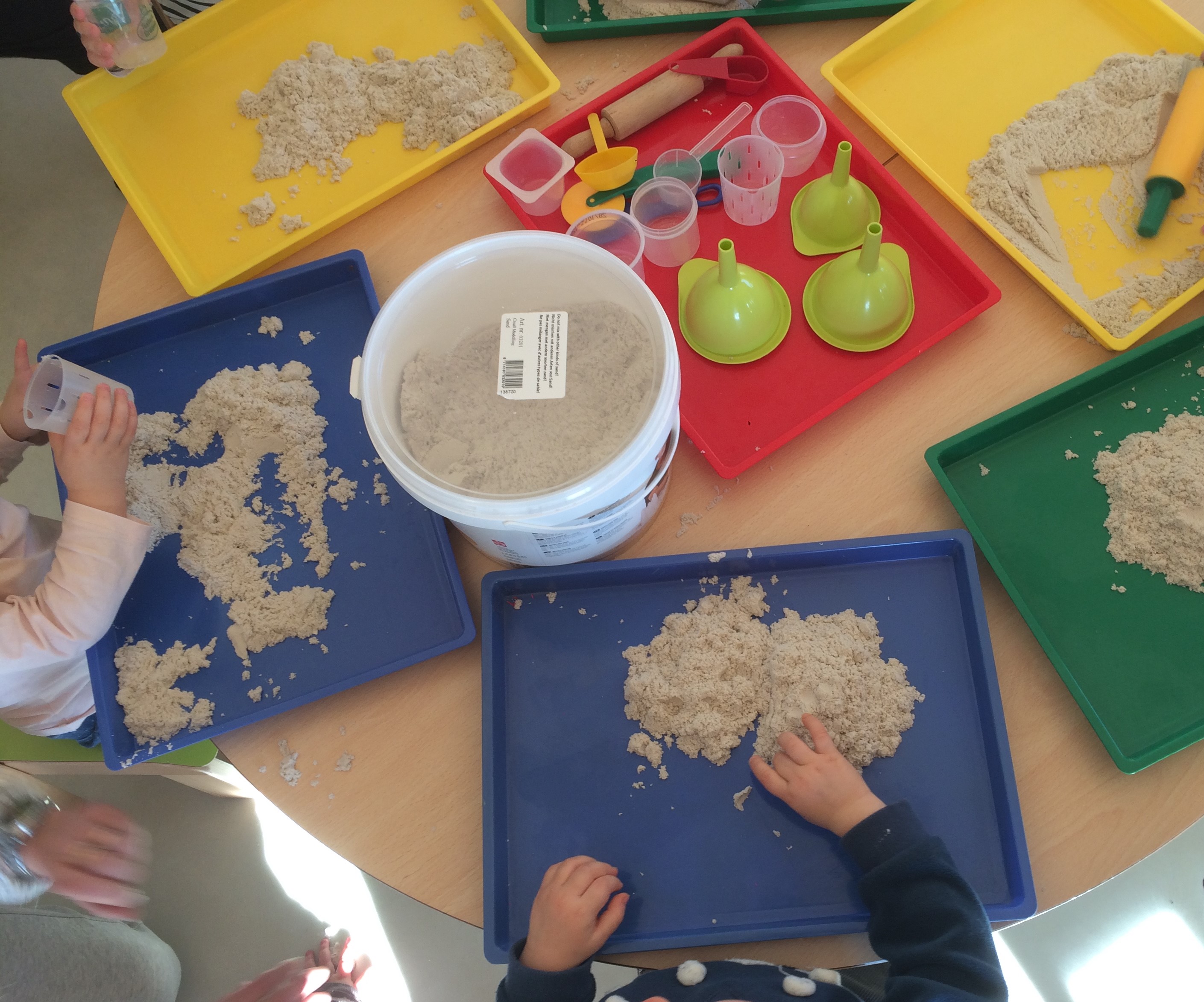Les enfants transvasent et manipulent du sable à modeler