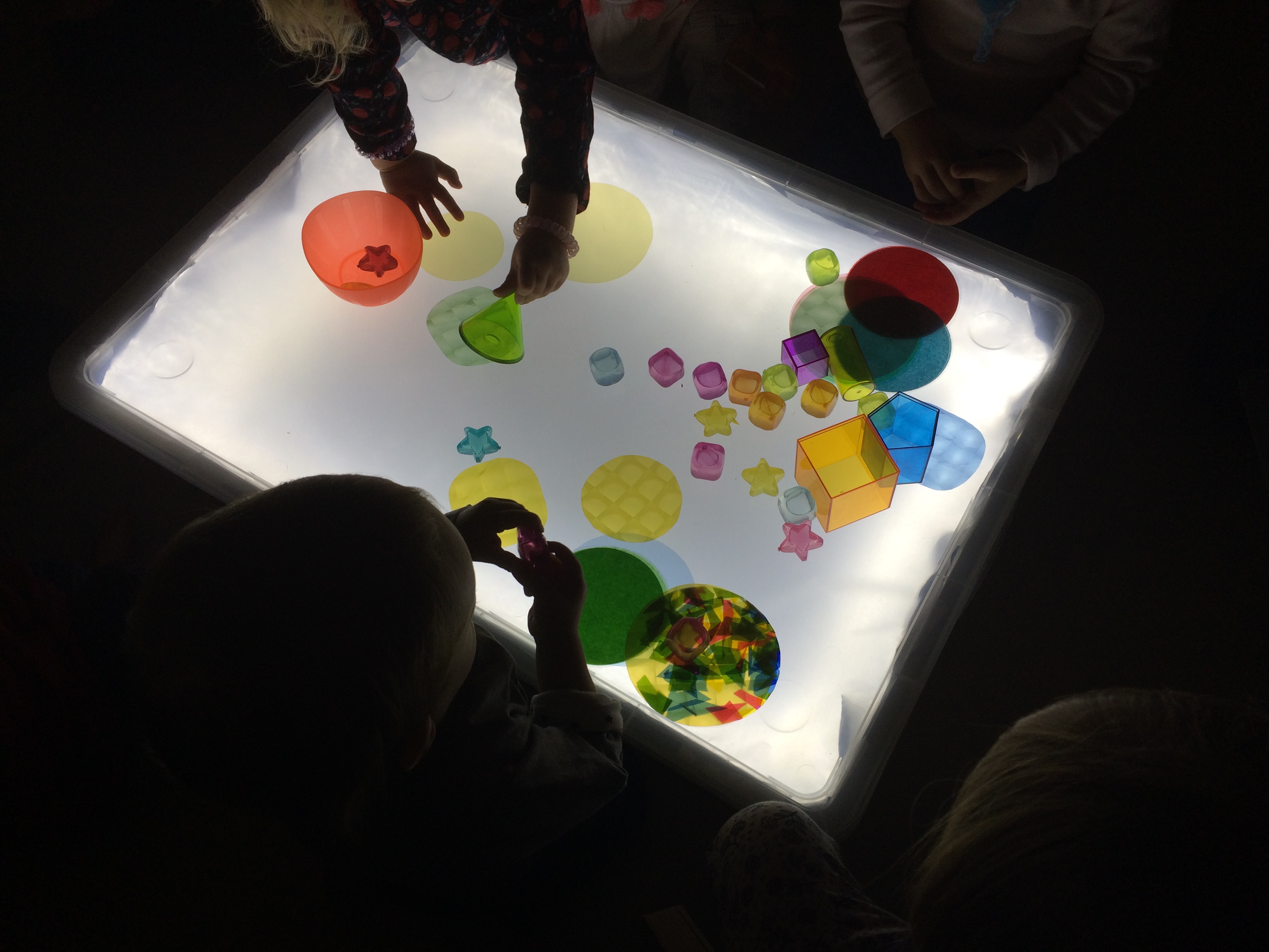 Table lumineuse : les enfants disposent des papiers de formes et couleurs diffentes