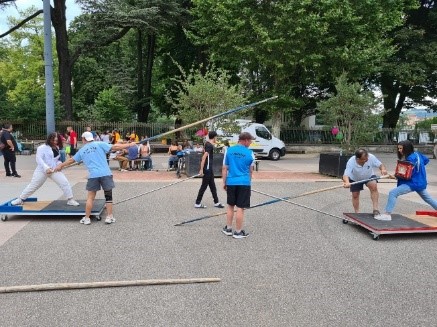 Des adultes s&#039;initient au sport de combat et athlétisme, guidés par un animateur, sur une grande place en extérieur