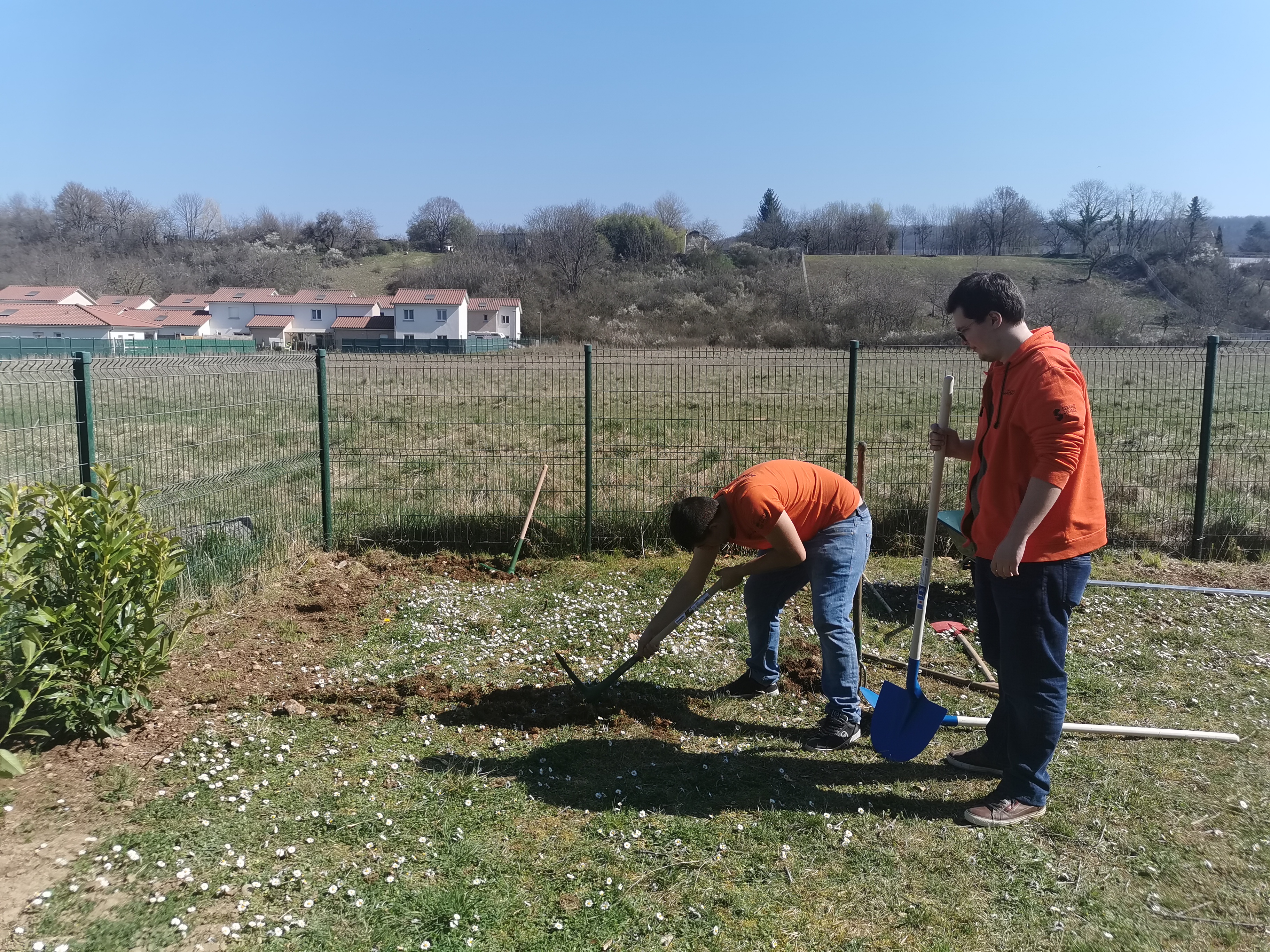 Deux bénévoles bêchent la terre pour préparer le jardin partagé