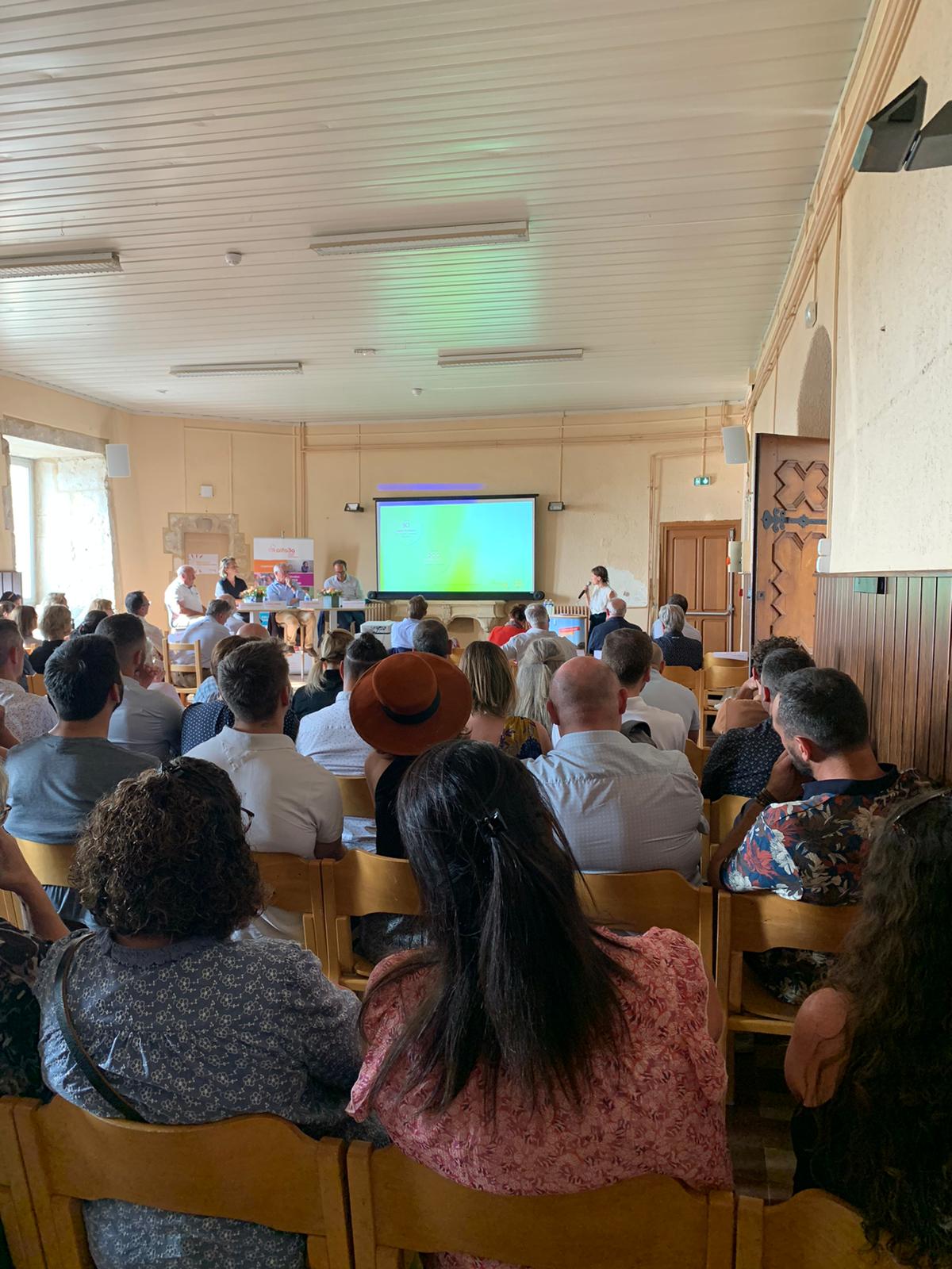 Vue de dos du public, en train d&#039;écouter la présentation orale dans une salle du château de Varey