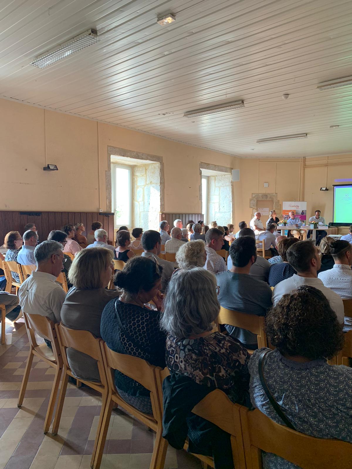 Vue de dos du public, en train d&#039;écouter la présentation orale dans une salle du château de Varey