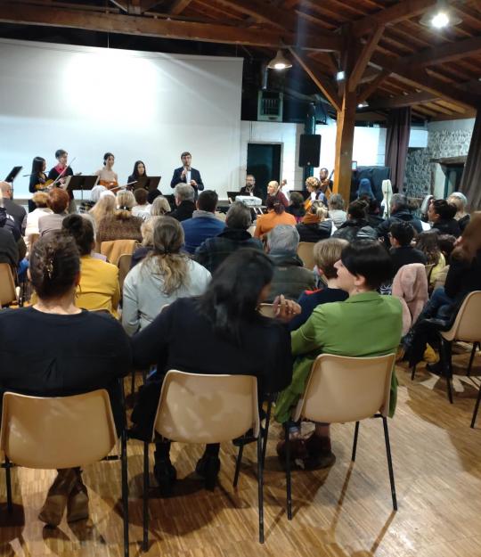 Des dizaines de personnes assistent, assis, aux vœux du maire de Vienne dans la salle de réception du centre social Malissol; un orchestre est sur scène avec lui