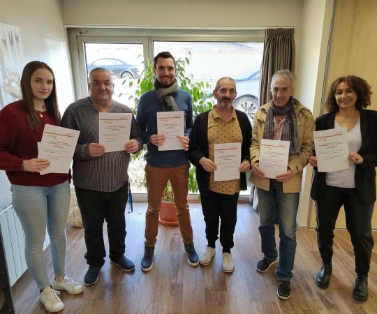 Jour de la signature : 3 bénévoles entourés de 3 salariés des pensions de famille, posent avec fierté pour la photo avec leurs contrat dans la main