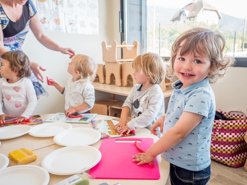 4 enfants installés devant la table, participe à un atelier où la pâte d’amande est travaillée comme de la pâte à modeler. Sous l’œil bienveillant de Sonia l’intervenante.