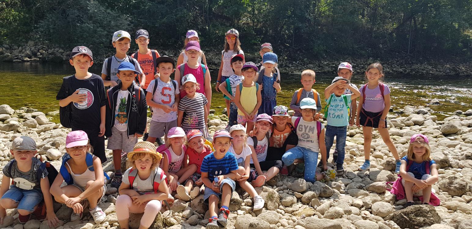 Un groupe d’enfants de 3 à 13 ans au bord d’une rivière en été lors d’une sortie