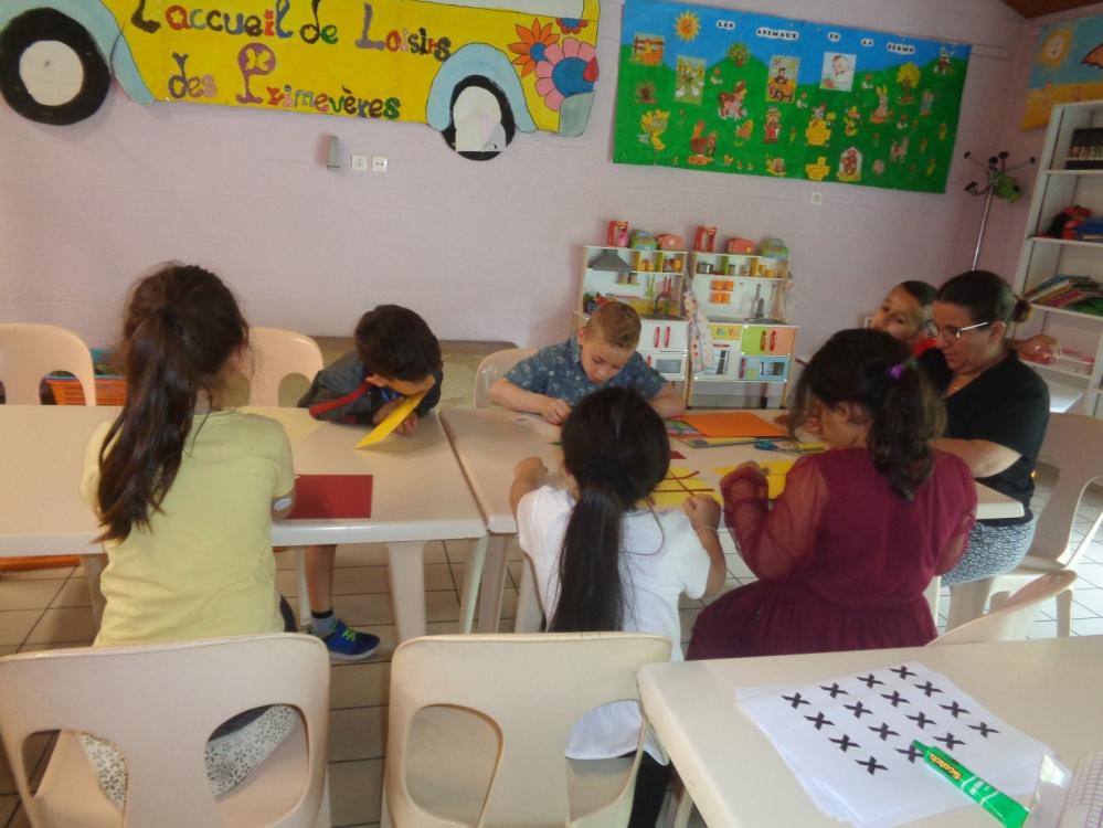 Un groupe d’enfants autour d’une table en train de réaliser une activité manuelle avec leur animatrice