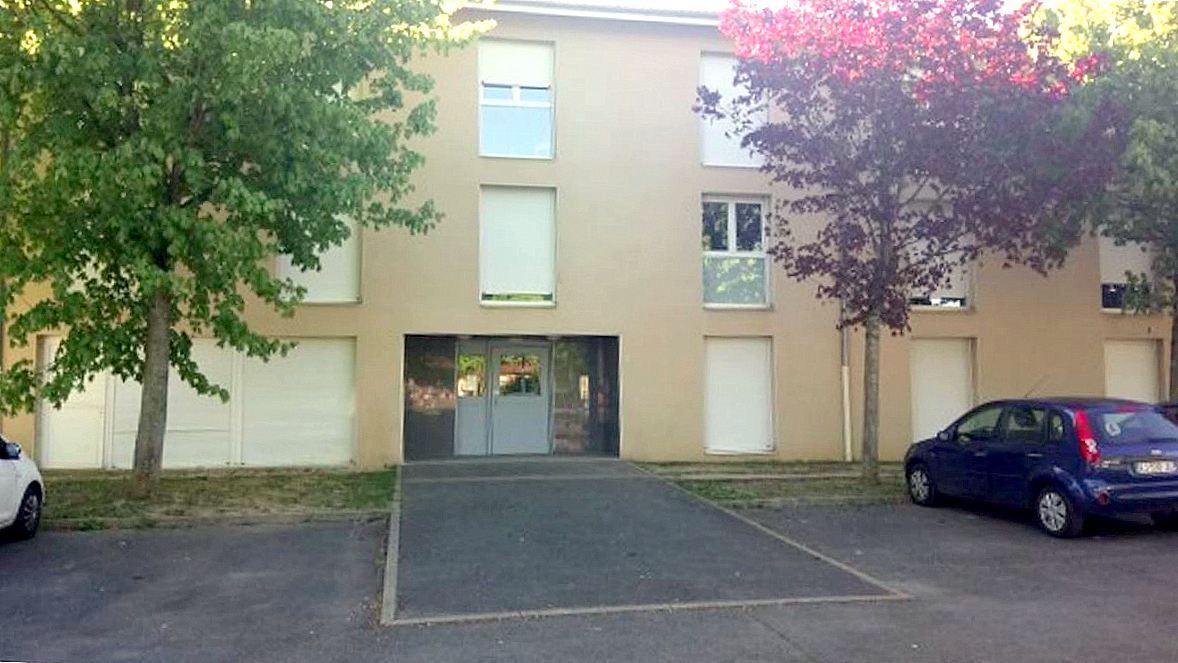 Entrée du bâtiment de la résidence Les Sardières, on peut voir son parking et ses espaces arborés