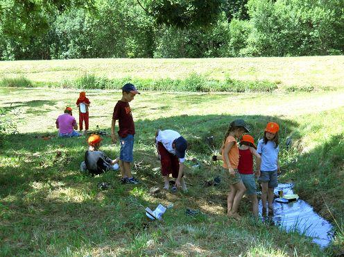 Groupe de jeunes enfants en sortie d’été au bord d’un petit ruisseau. Mise à l’eau des bateaux fabriqués avec les éléments de récupération.